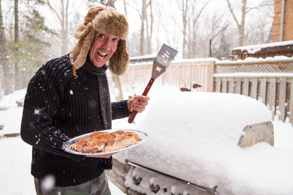 A man in a furred hat getting ready to grill on the barbecue
