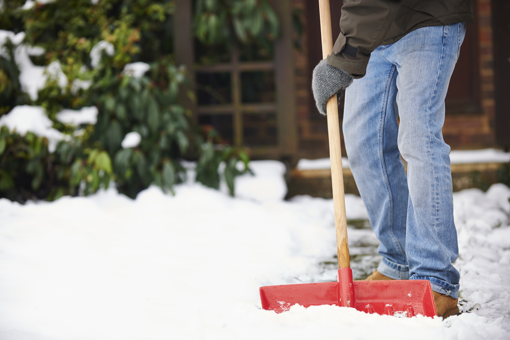 Close-up of a man's legs as he shovels snow