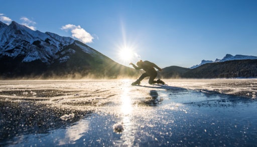 Elladj Balde gets ready to skate on a frozen lake in the mountains with the sunrise behind