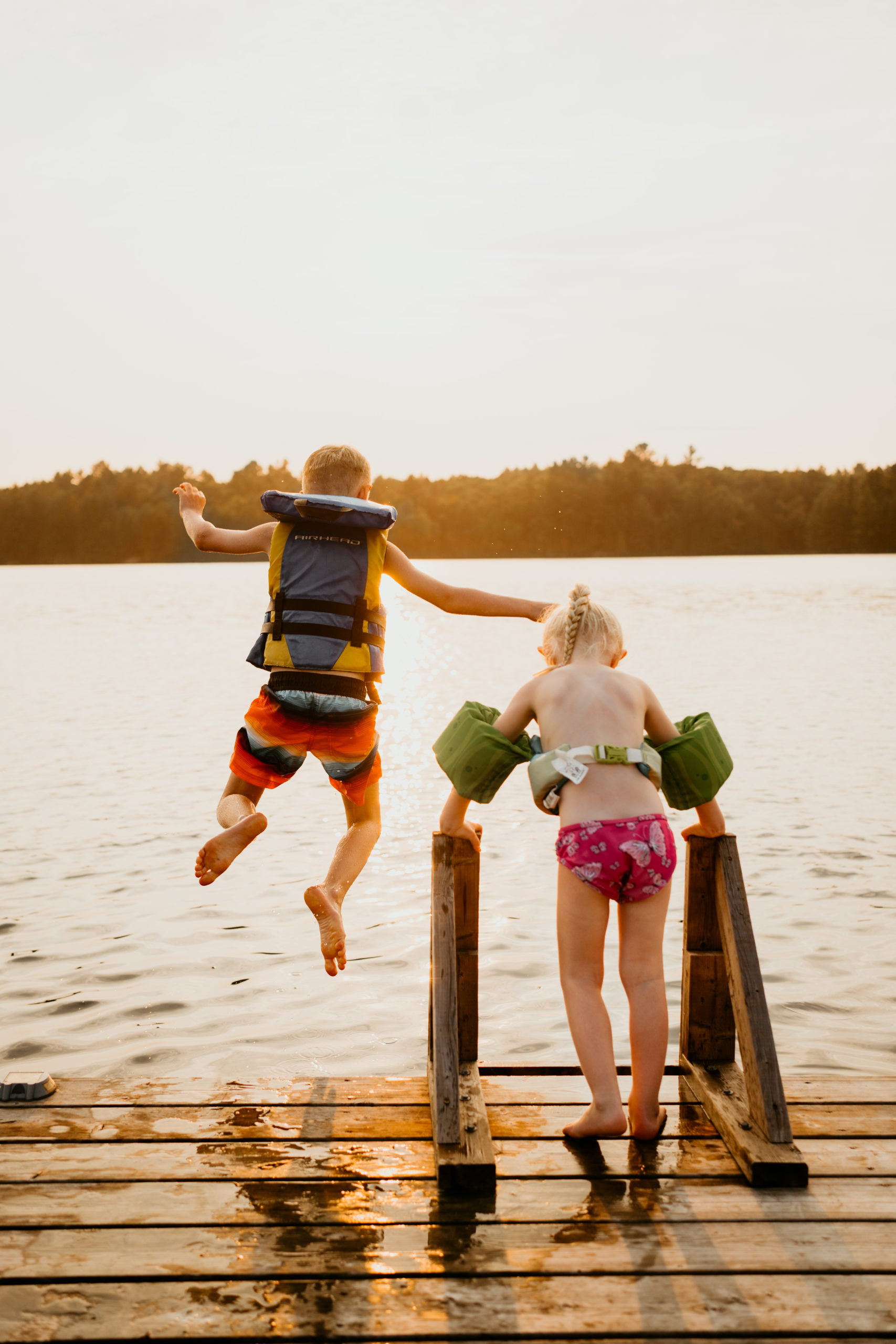 Two kids jumping off of dock