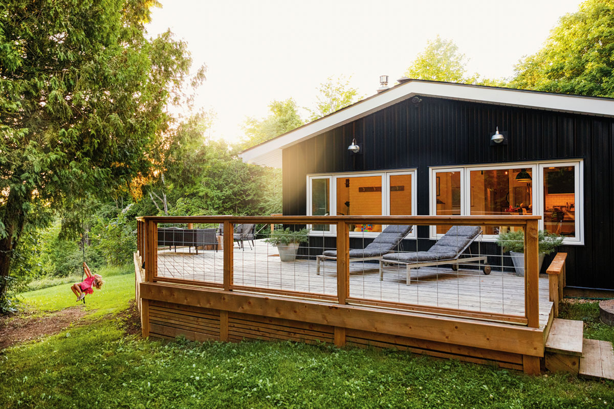 exterior shot of Raina and Wilson's shared cottage with sun setting in the background and child playing on a rope swing