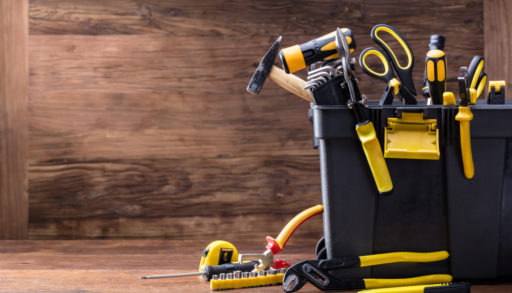A large tool caddy filled with tools against a wooden wall