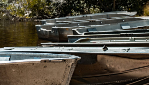 Several old aluminum boats lined up at a dock