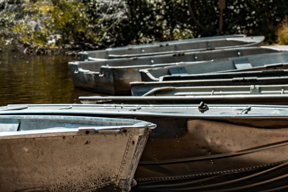 Several old aluminum boats lined up at a dock