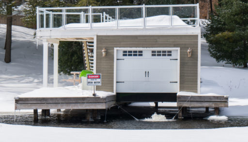 A boathouse surrounded by open water in a frozen lake