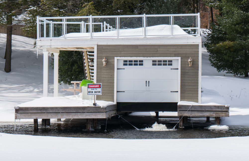 A boathouse surrounded by open water in a frozen lake