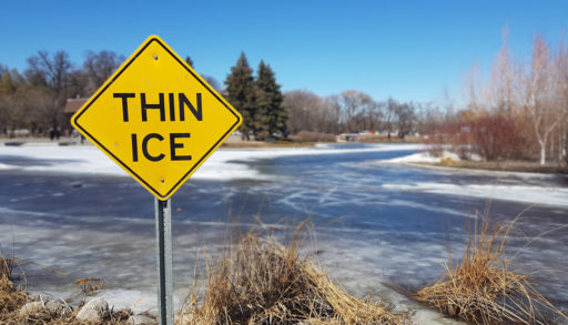 yellow thin ice sign by frozen lake