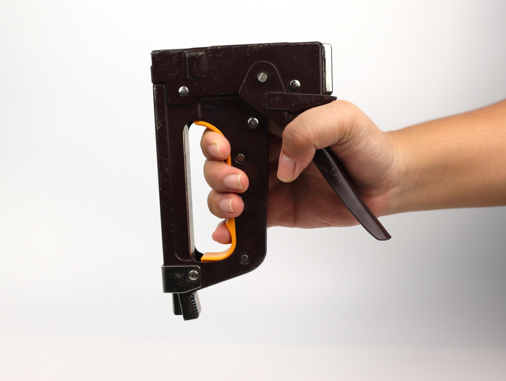A hand holding a heavy-duty stapler