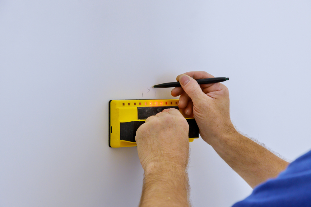 Close-up of male hands using an electronic stud finder on a wall