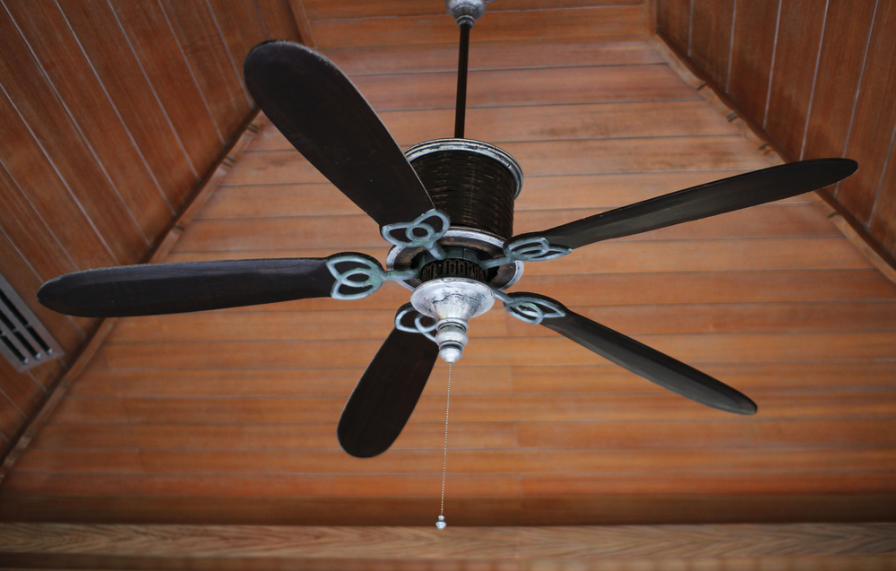 A electric ceiling fan suspended from a vaulted ceiling