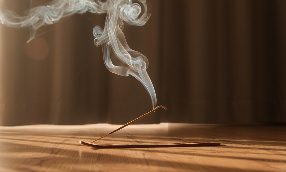 A stick of smoking incense on a wooden table