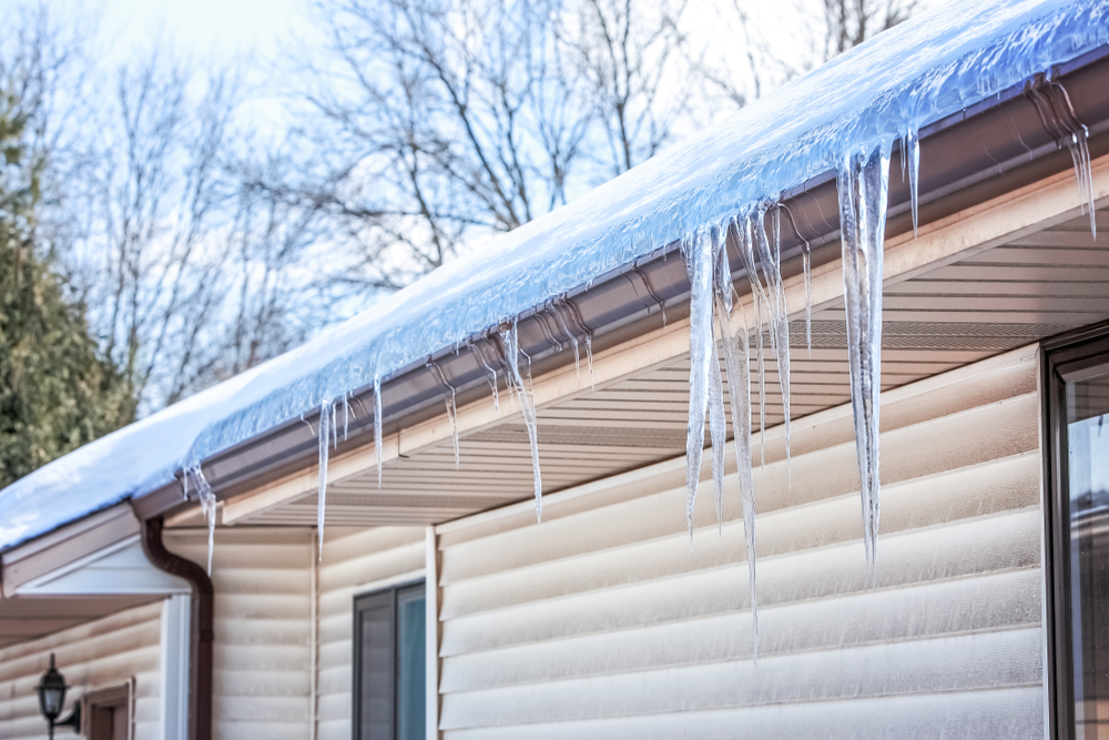 Ice and icicles clinging to the roof edge of a home