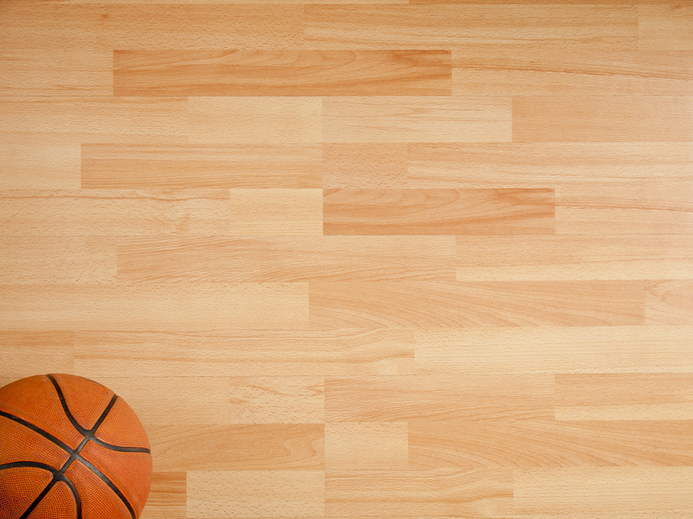 A basketball on one corner of a plywood floor