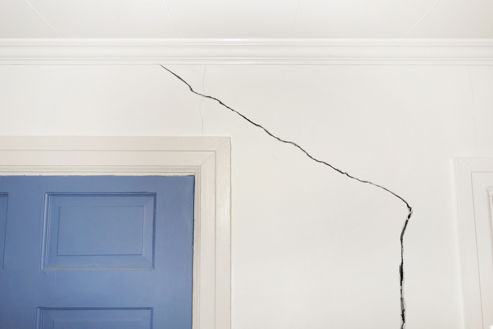 A white interior wall with a long corner crack
