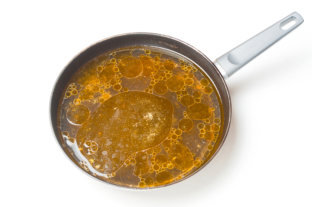 A grease-filled frying pan against a white background