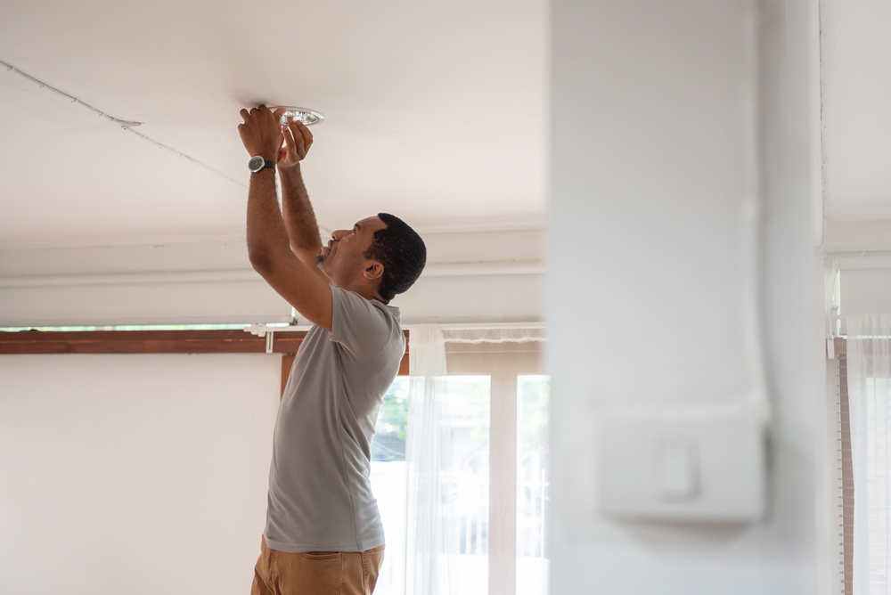 An African American male replacing an LED lamp fixture