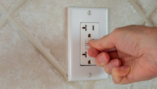 Closeup of fingers resetting a GFCI