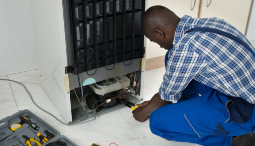 Young African American man fixing a refrigerator