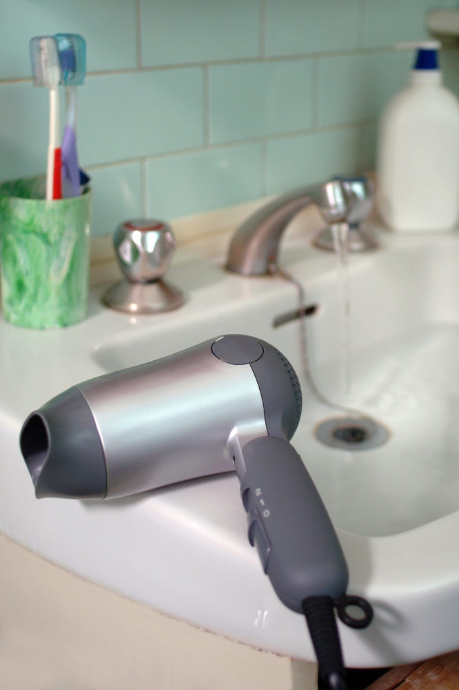 A hairdryer resting beside a sink full of water