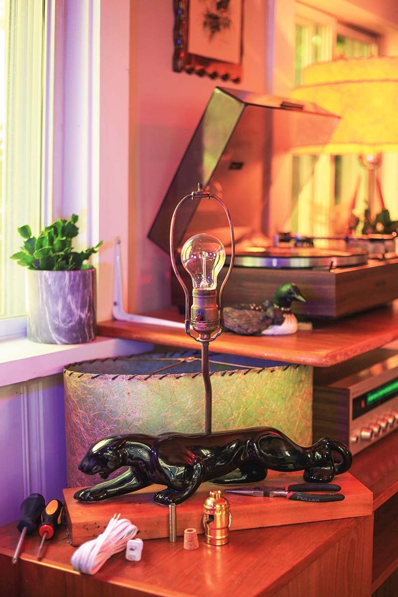 a lamp with the shade off in the corner of a living room with a record player behind it