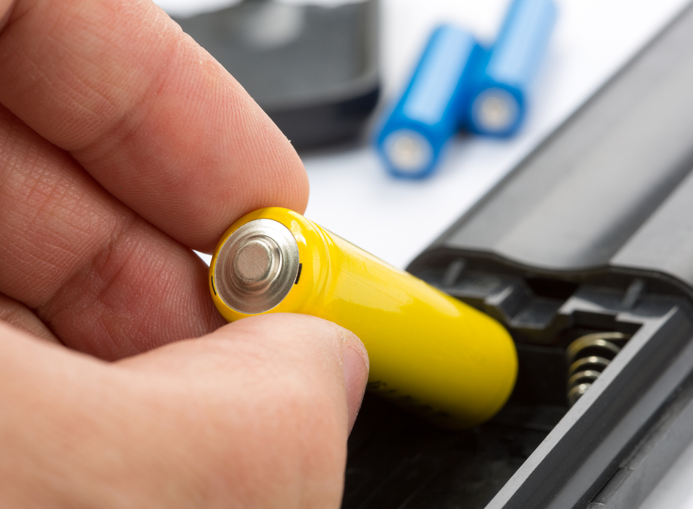A close-up of fingers removing a battery from a remote control