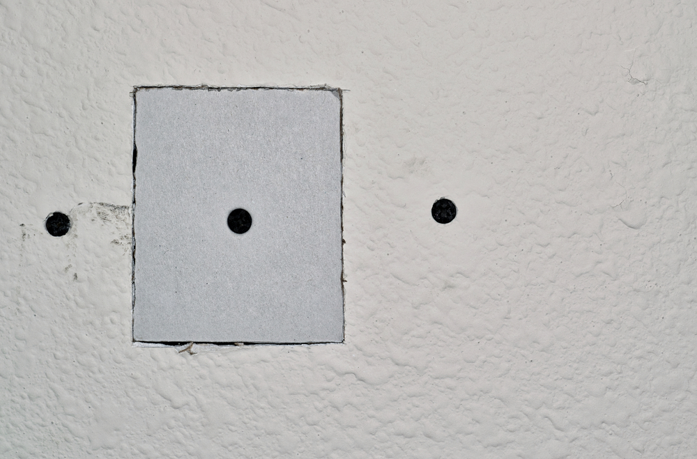 A square patch screwed in place over a hole in the wall