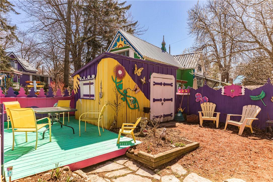 Wide outdoor space with a stone patio, turquoise wood deck and a purple and yellow shed with a pink flower decal.