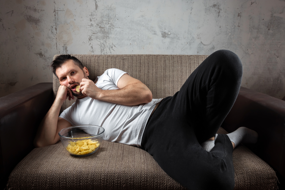 Man lounging on the couch eating chips