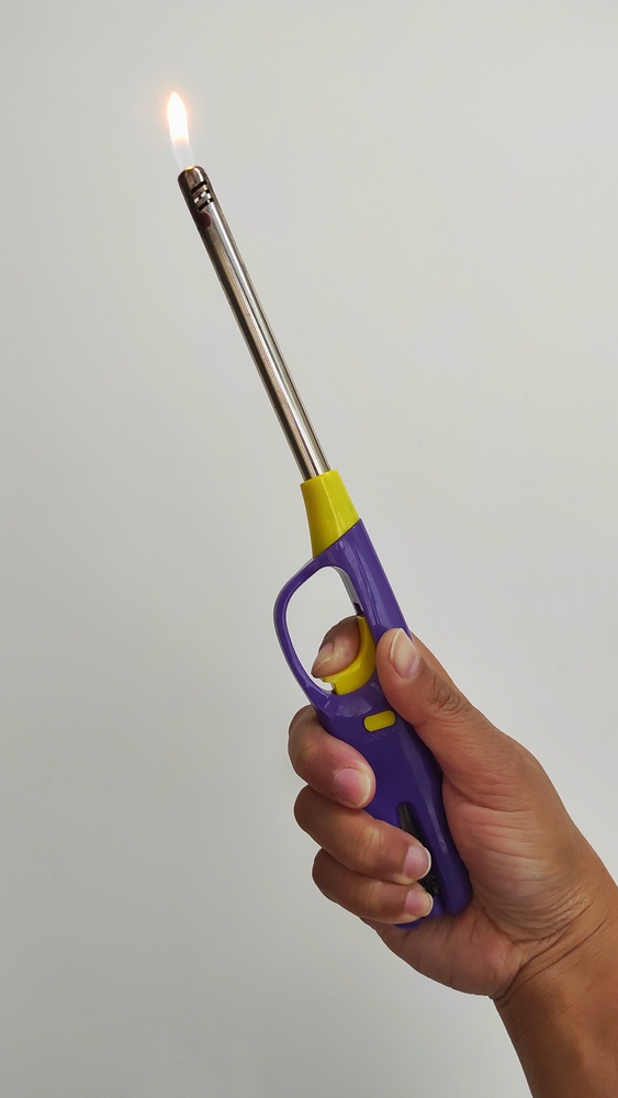 A hand holding a a lighter for a propane barbecue