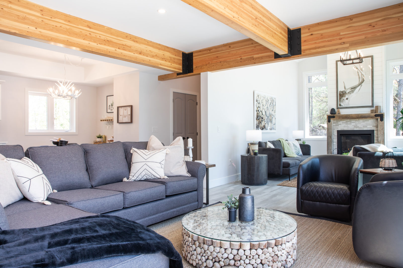 An open living area with a large grey couch and a sunny seating area in the background.