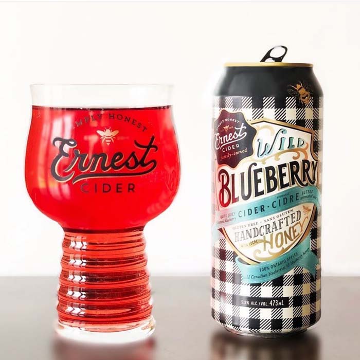 Ernest Cider Wild Blueberry cider in a glass next to the can
