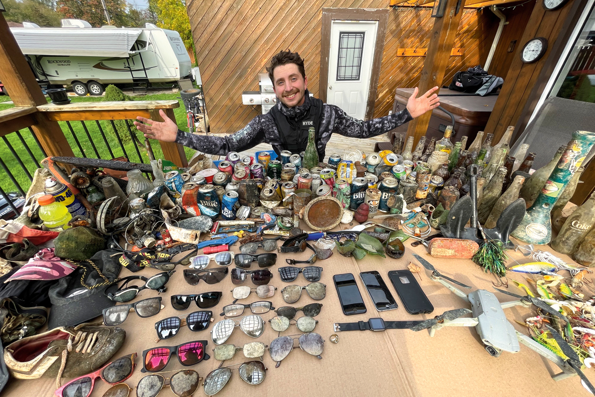 A scuba diver surrounded by items he pulled out of the lake