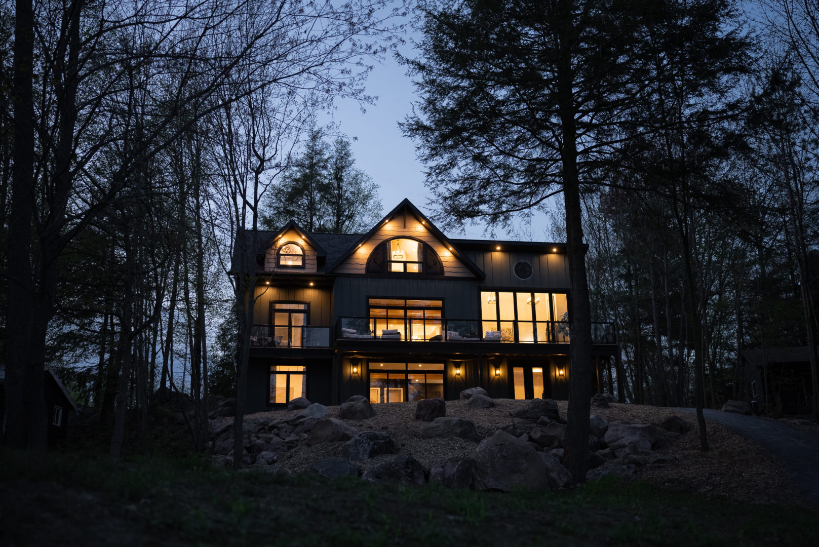 A large cottage at nighttime, with warm white lights shining from inside.