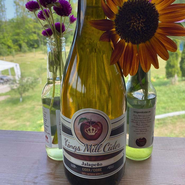 kings mill cider in a big bottle in front of two flower vases