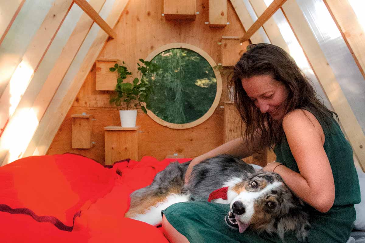 a woman and a dog sitting on the bed inside the bird hut