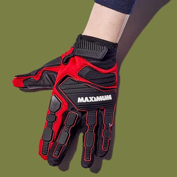 A hand wearing a black and red MAXIMUM heavy duty impact glove against a camo-green background.
