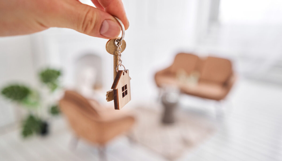 a person holding a key with a house charm