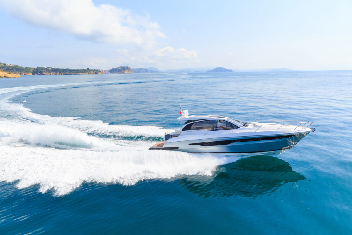 Luxury motor boat speeds through blue water making wake.