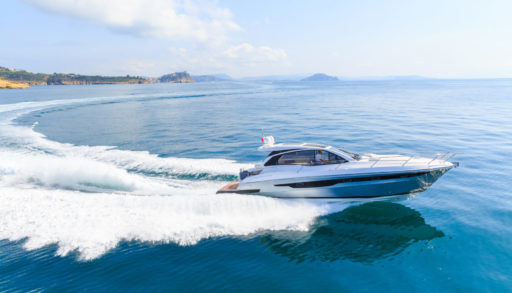 Luxury motor boat speeds through blue water making wake.