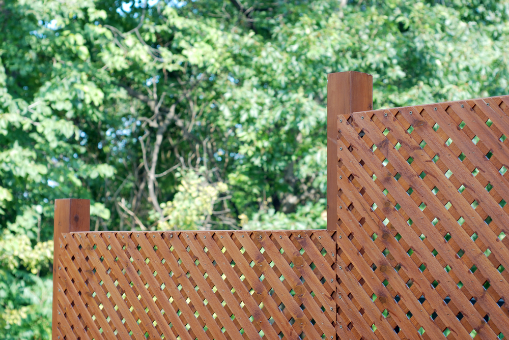 A wooden lattice fence with trees in the background