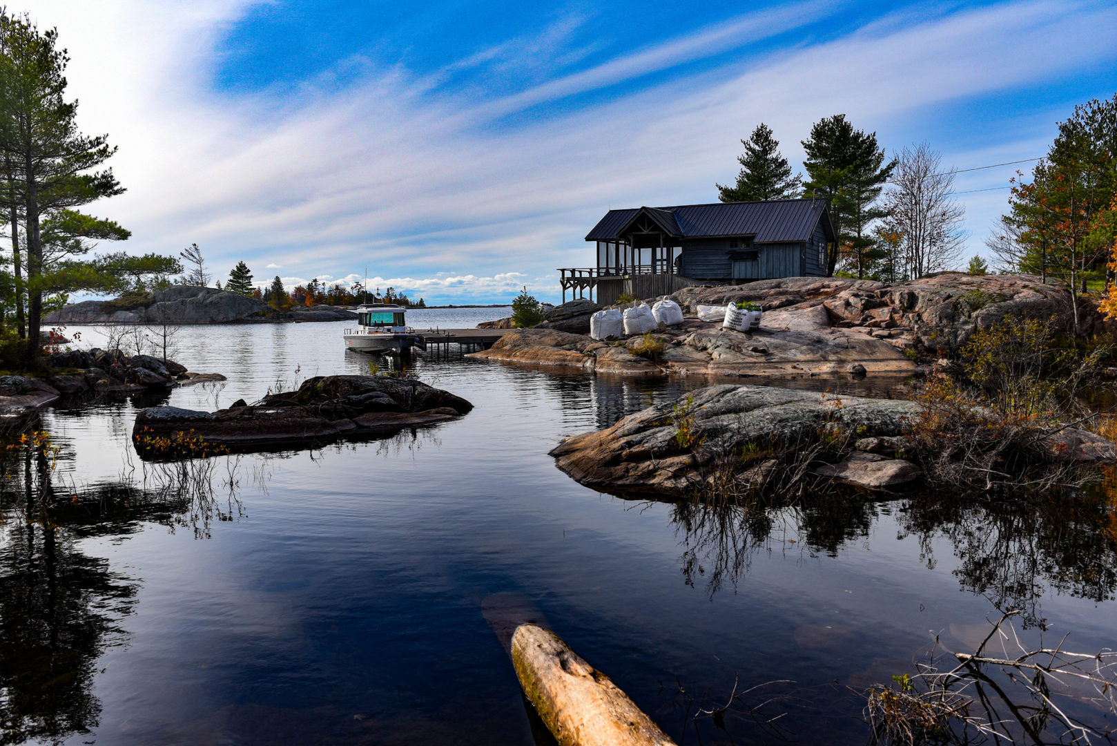 Photo contest entry of a wide angle shot of cottage sitting on bedrock next to a lake.