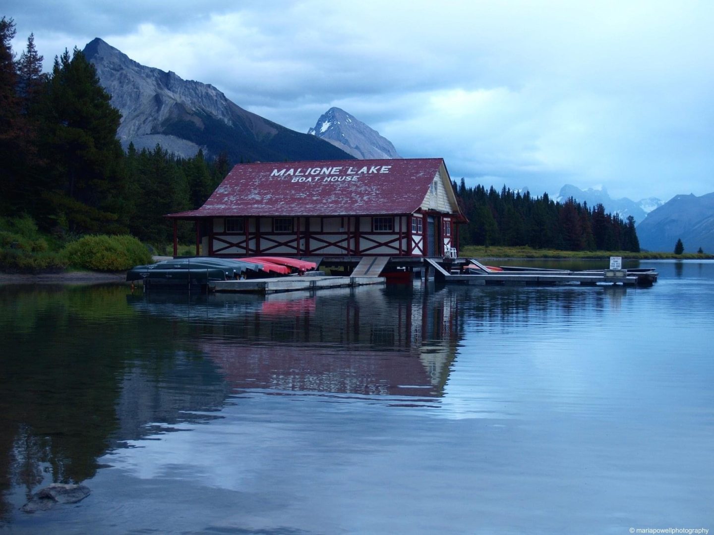 Photo contest entry of a lakeside cottage in front of mountains.