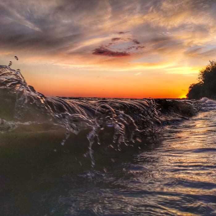 Close-up of a wave crashing on the shores of Lake Erie while the sun sets