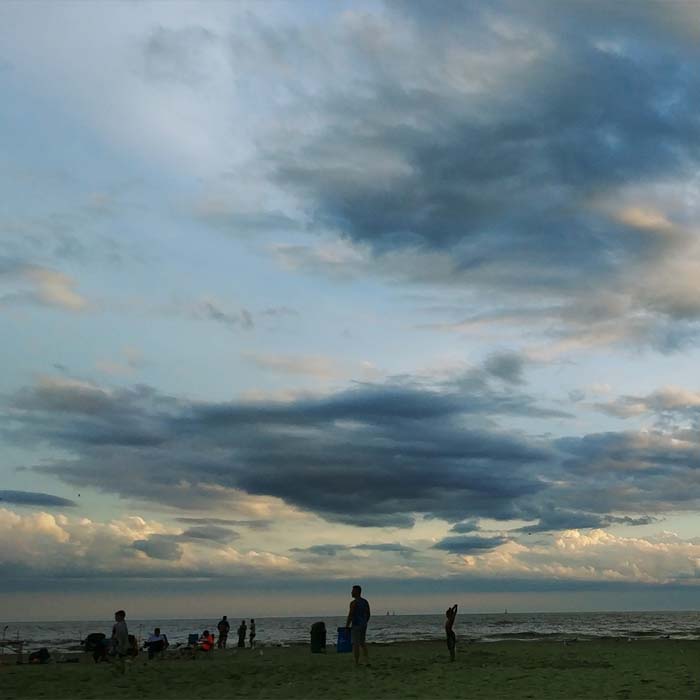 people relaxing at Port Dover beach as the sun goes down in front of Lake Erie