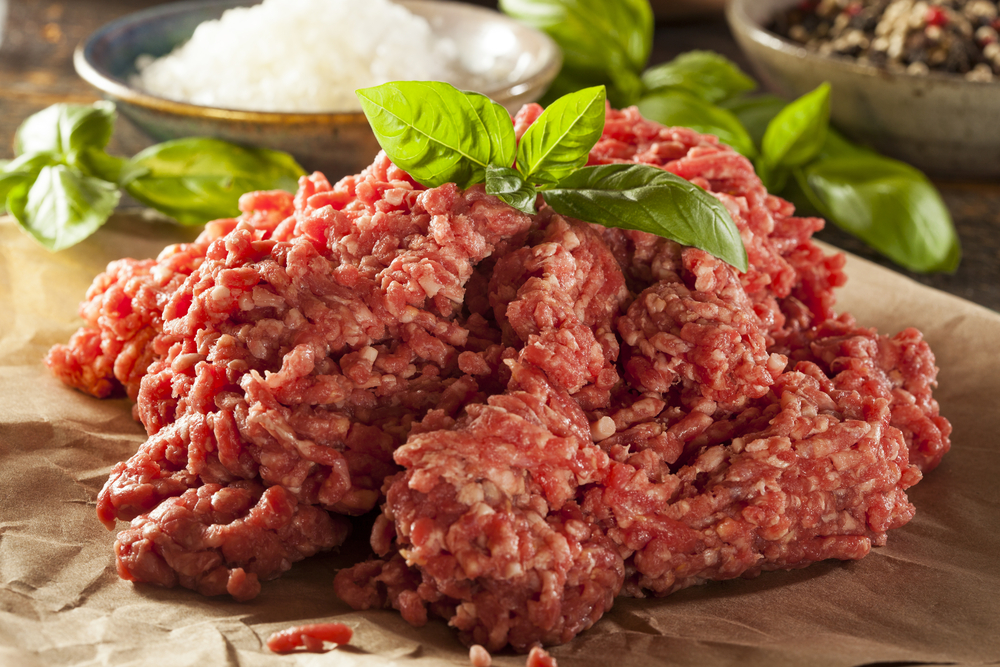 A pile of ground beef garnished with greens