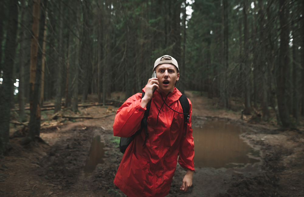 A frightened man talking on a cell phone in the woods