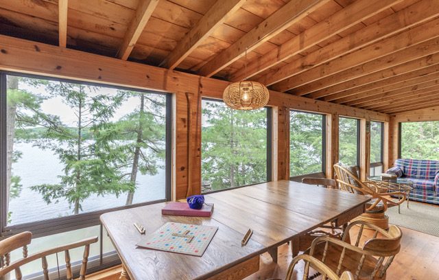 interior of a screen porch at a cottage looking out at the lake