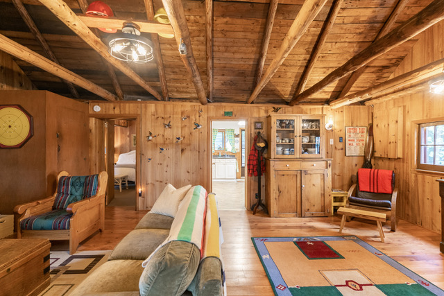 interior of a living room with a big fireplace, a plaid couch, and a tv