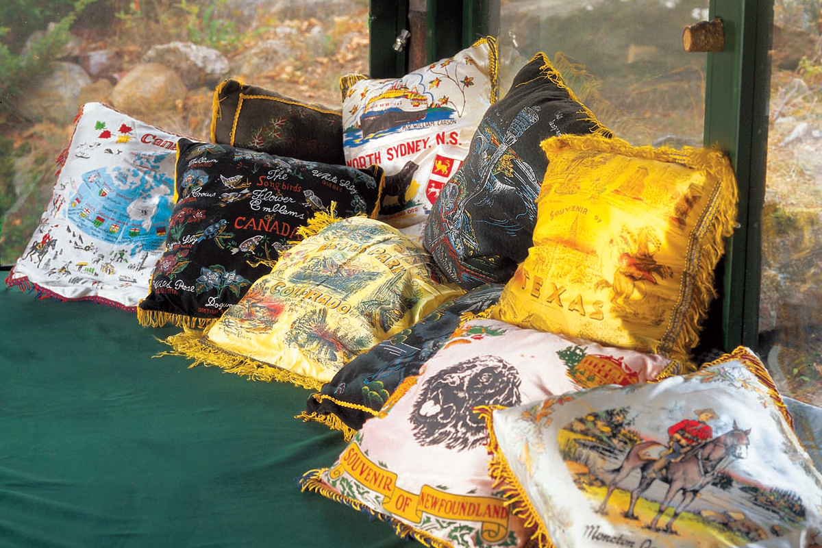 a collection of silk pillows on a cottage screened porch