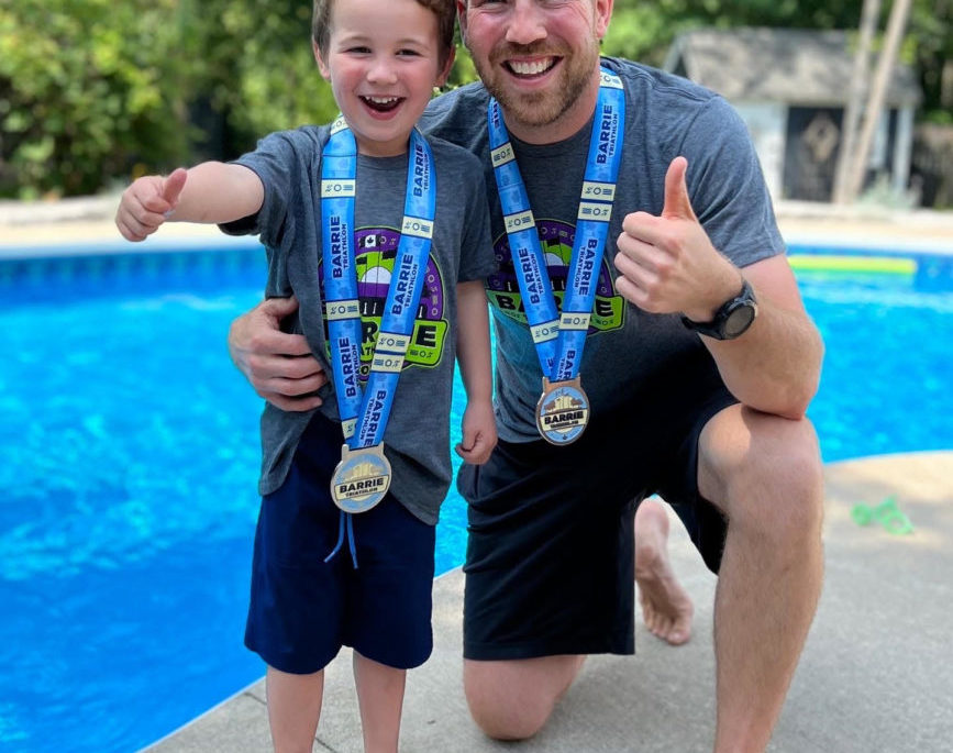 Adam Holman and his son show off their triathlon medals.